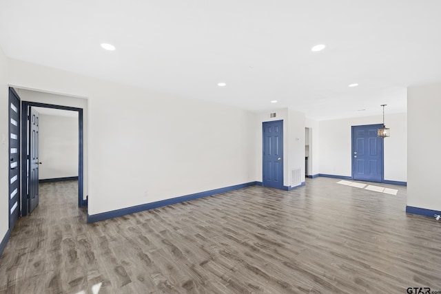 unfurnished living room featuring recessed lighting, wood finished floors, and baseboards