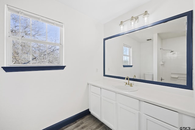 bathroom with toilet, baseboards, wood finished floors, and vanity