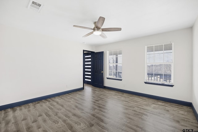 unfurnished room with baseboards, visible vents, ceiling fan, and wood finished floors