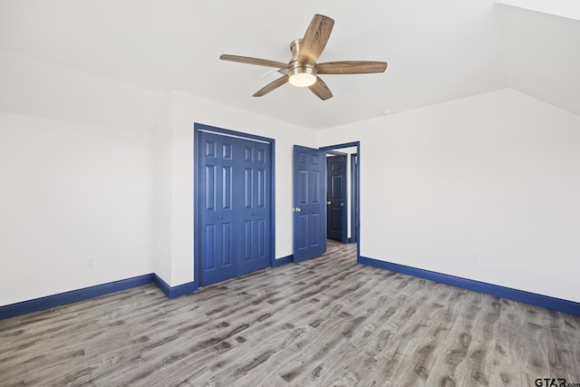 unfurnished bedroom featuring light wood finished floors, baseboards, a ceiling fan, lofted ceiling, and a closet