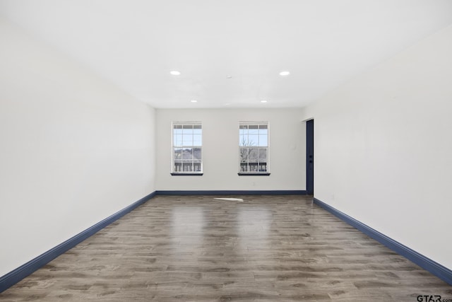 empty room with recessed lighting, wood finished floors, and baseboards