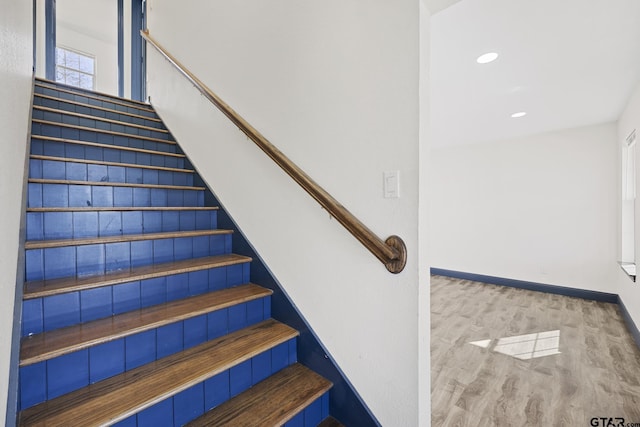 staircase with baseboards, wood finished floors, and recessed lighting