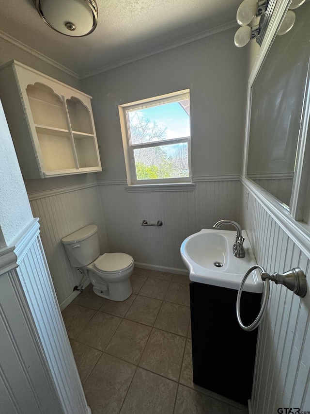 bathroom with a wainscoted wall, vanity, toilet, and tile patterned floors