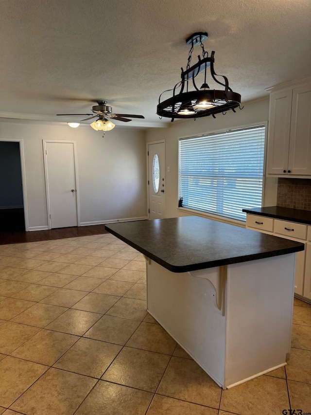 kitchen featuring a kitchen island, white cabinetry, a kitchen breakfast bar, hanging light fixtures, and dark countertops