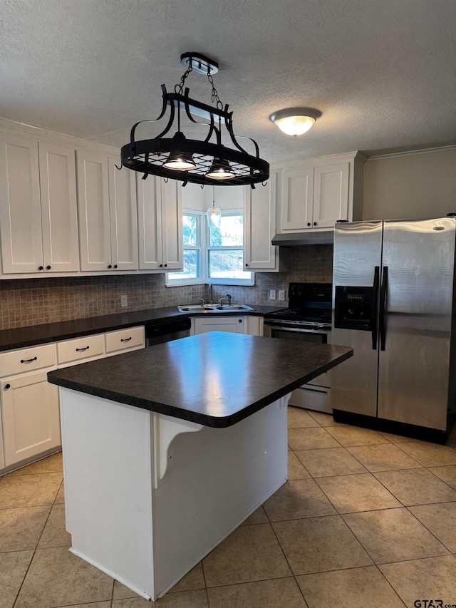 kitchen featuring white cabinets, dark countertops, appliances with stainless steel finishes, a center island, and pendant lighting