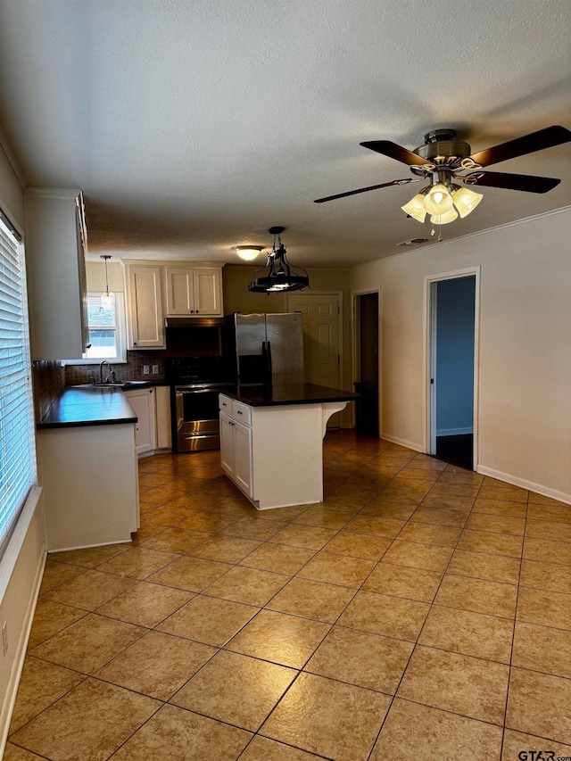 kitchen with a center island, decorative light fixtures, stainless steel appliances, dark countertops, and a sink