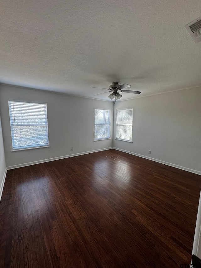 empty room with baseboards, dark wood finished floors, visible vents, and a ceiling fan