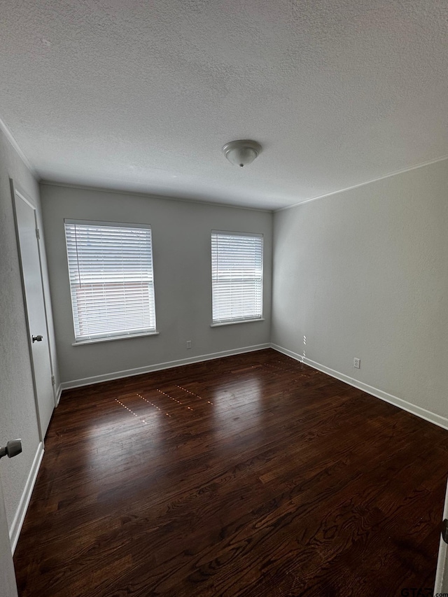 empty room featuring a textured ceiling, baseboards, and dark wood-style flooring