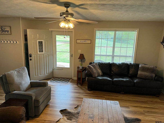 living room with light wood-type flooring, a textured ceiling, and ceiling fan