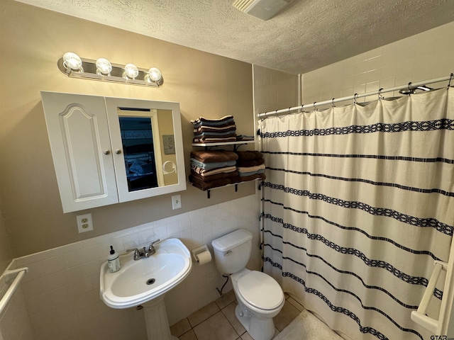 bathroom featuring toilet, tile walls, tile patterned flooring, a textured ceiling, and sink