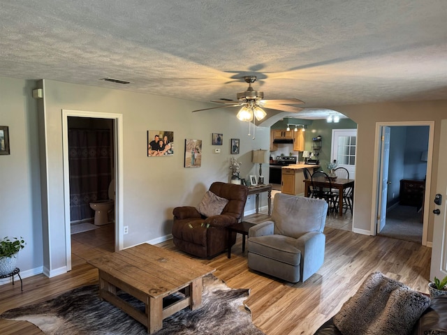 living room featuring light hardwood / wood-style flooring, a textured ceiling, and ceiling fan