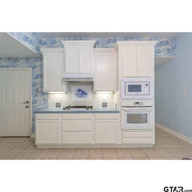 2060 Rana Park, Flint, TX 75762 - kitchen with white appliances, tile countertops, under cabinet range hood, wallpapered walls, and white cabinetry