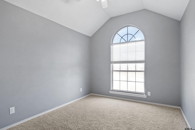 carpeted spare room with ceiling fan and vaulted ceiling