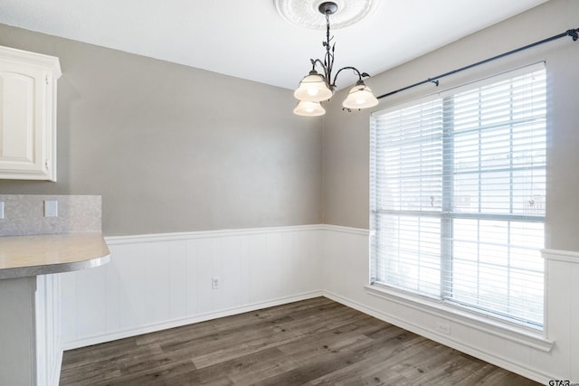 unfurnished dining area featuring dark wood-type flooring, a chandelier, and plenty of natural light