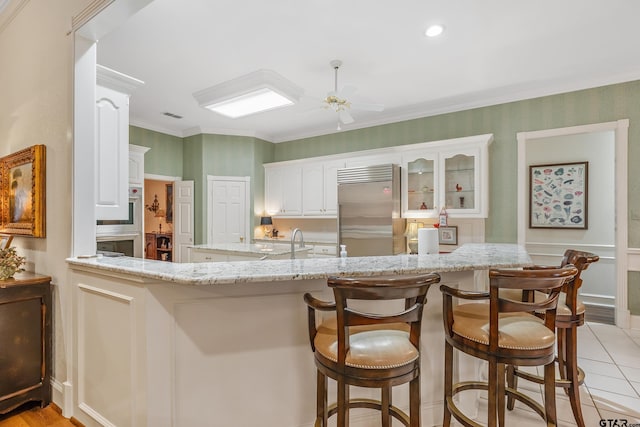 4831 Barclay Dr, Tyler, TX 75703 - kitchen featuring high end fridge, light stone countertops, a peninsula, a ceiling fan, and a sink