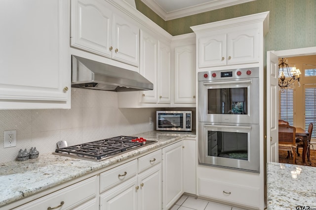 4831 Barclay Dr, Tyler, TX 75703 - kitchen with stainless steel appliances, under cabinet range hood, a chandelier, white cabinetry, and crown molding