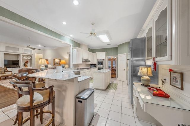 4831 Barclay Dr, Tyler, TX 75703 - kitchen featuring ceiling fan, a peninsula, stainless steel appliances, crown molding, and a kitchen breakfast bar