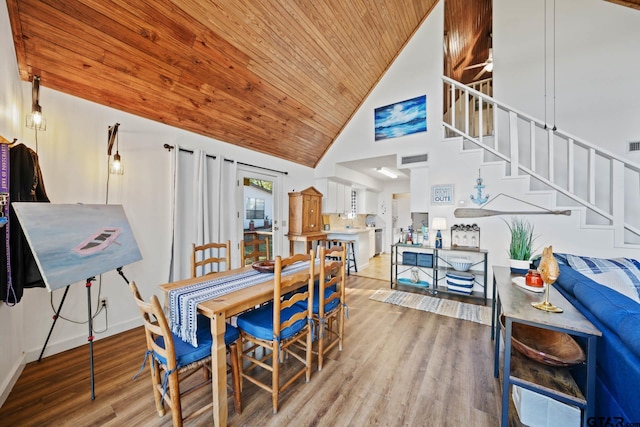 dining room with light wood-type flooring, high vaulted ceiling, and wooden ceiling