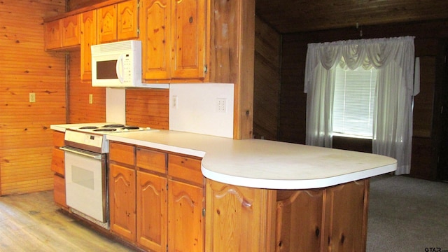 kitchen with kitchen peninsula, wooden walls, light hardwood / wood-style flooring, and white appliances