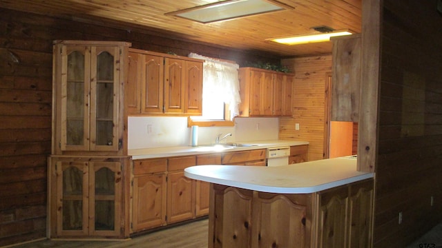 kitchen with sink, wooden walls, a skylight, light wood-type flooring, and kitchen peninsula