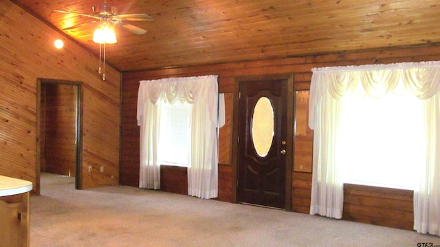 carpeted entrance foyer featuring wooden ceiling, wooden walls, ceiling fan, and a healthy amount of sunlight