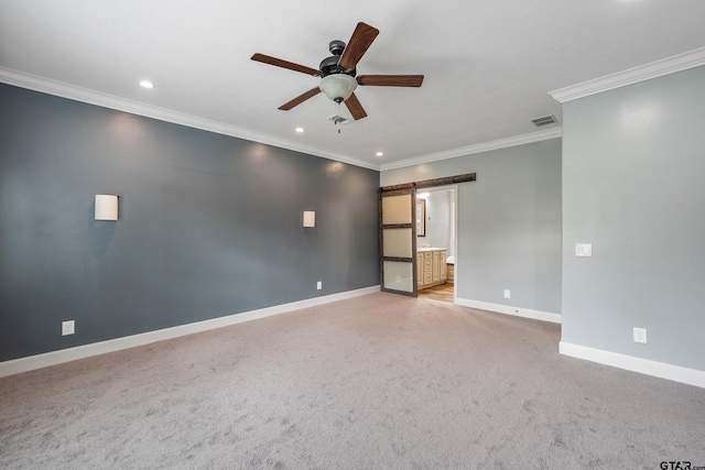 carpeted empty room featuring a barn door, ceiling fan, and crown molding