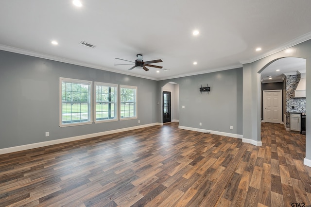 unfurnished living room with ceiling fan, dark wood-type flooring, and ornamental molding