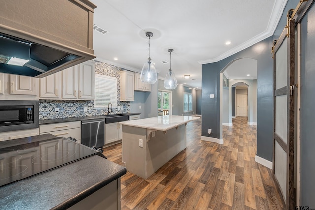 kitchen with a center island, a barn door, dark hardwood / wood-style floors, pendant lighting, and black appliances