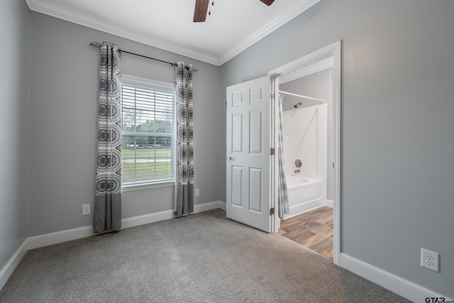 unfurnished bedroom featuring light carpet, ensuite bath, ceiling fan, and crown molding