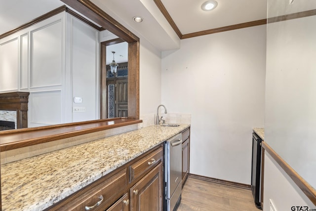 kitchen with sink, a stone fireplace, light hardwood / wood-style flooring, crown molding, and white cabinets