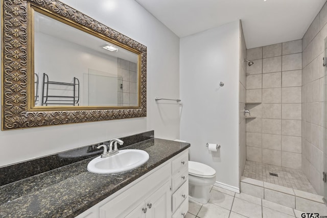 bathroom with tile patterned floors, vanity, a tile shower, and toilet