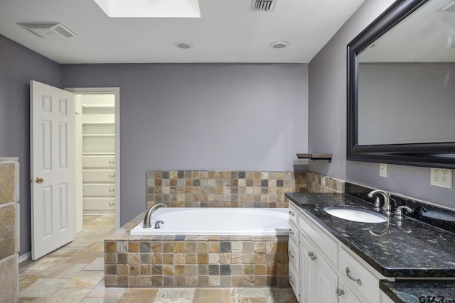 bathroom with vanity and tiled bath