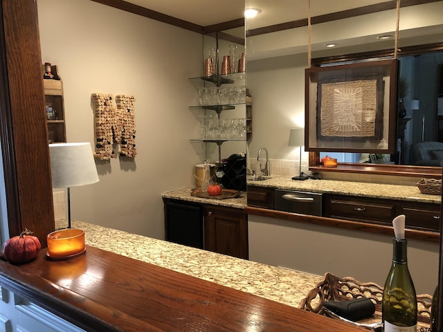 bar featuring light stone countertops, dark brown cabinets, and sink