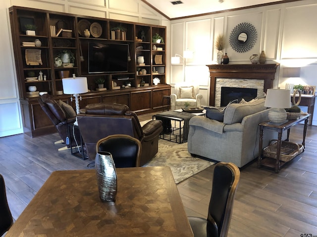 living room featuring ornamental molding, wood-type flooring, a fireplace, and vaulted ceiling