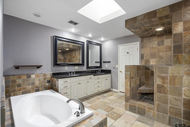 bathroom featuring vanity, tiled bath, and a skylight