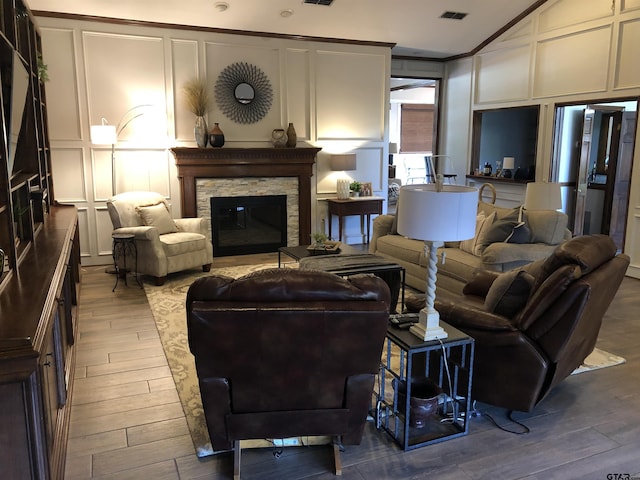 living room with lofted ceiling, ornamental molding, and a fireplace