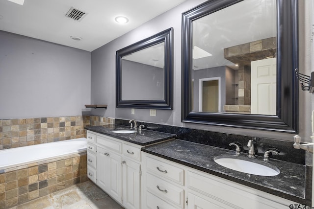 bathroom featuring tiled tub and vanity