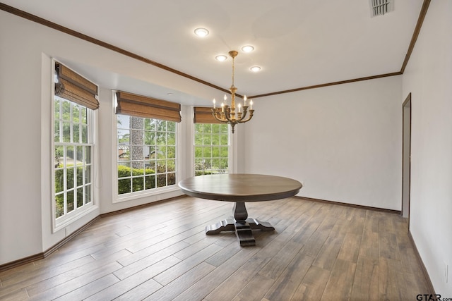 unfurnished dining area featuring wood-type flooring, crown molding, and a notable chandelier