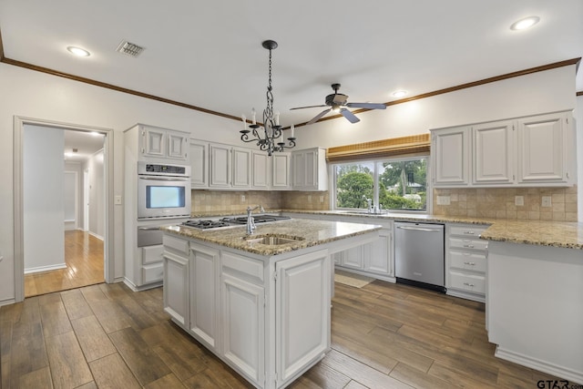 kitchen featuring appliances with stainless steel finishes, backsplash, a center island with sink, decorative light fixtures, and white cabinets