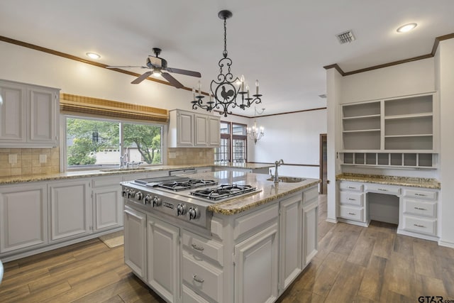 kitchen featuring dark hardwood / wood-style flooring, decorative light fixtures, a kitchen island, and stainless steel gas cooktop