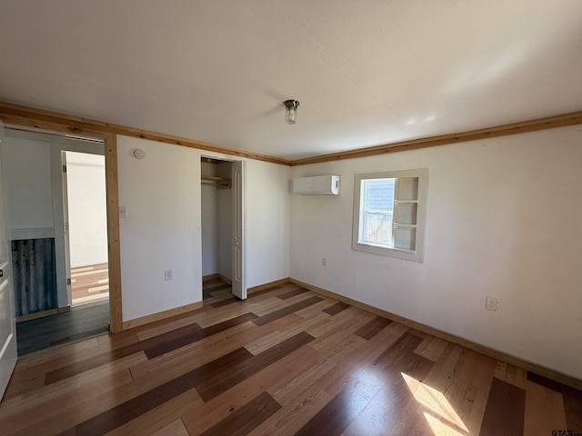 unfurnished bedroom featuring baseboards, a closet, wood finished floors, and an AC wall unit