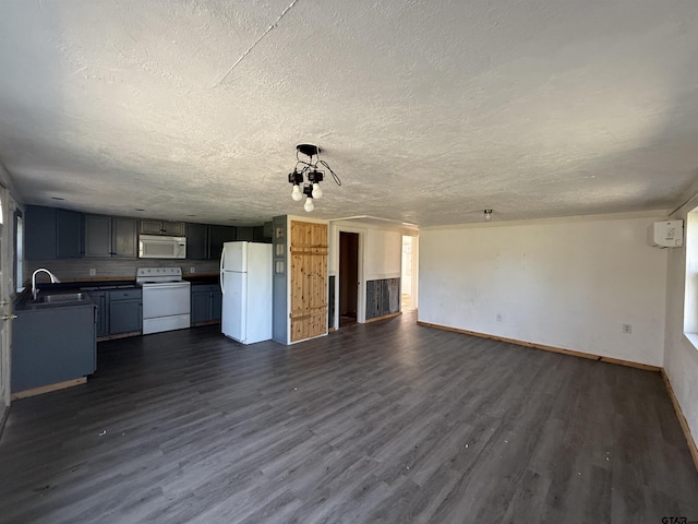kitchen featuring a sink, dark wood-style floors, open floor plan, white appliances, and dark countertops