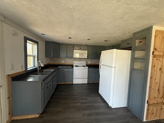 kitchen featuring white appliances, gray cabinets, dark wood-style flooring, a sink, and dark countertops