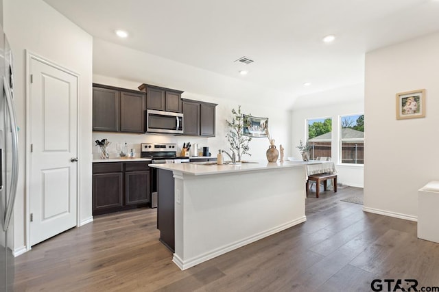 203 Parker Oaks Dr, Chandler, TX 75758 - kitchen with appliances with stainless steel finishes, dark brown cabinets, dark wood-style floors, light countertops, and a center island with sink