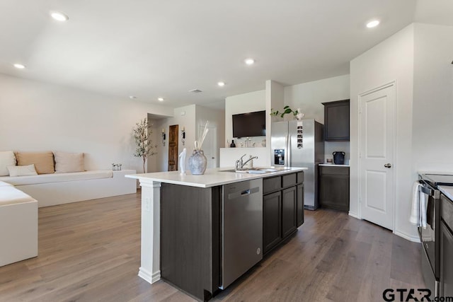 203 Parker Oaks Dr, Chandler, TX 75758 - kitchen with stainless steel appliances, open floor plan, wood finished floors, a kitchen island with sink, and light countertops