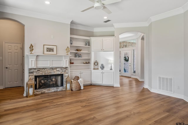 629 Whiteoak Ln, Tyler, TX 75703 - living room with arched walkways, ceiling fan, light wood-type flooring, a stone fireplace, and crown molding