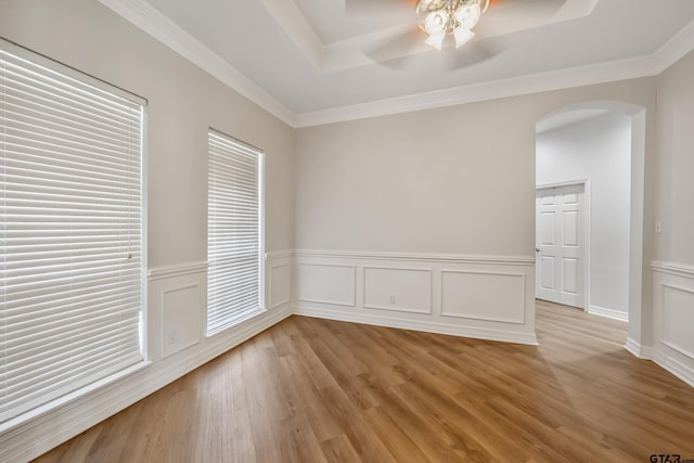 629 Whiteoak Ln, Tyler, TX 75703 - unfurnished room featuring arched walkways, ceiling fan, a tray ceiling, light wood-style floors, and a wainscoted wall