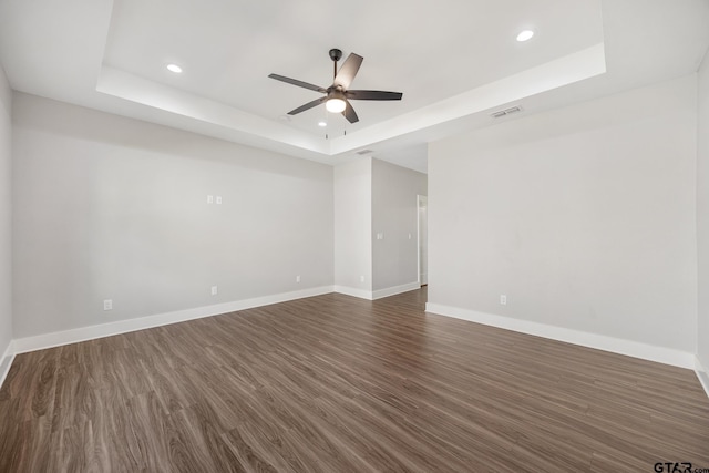 spare room featuring ceiling fan, a raised ceiling, and dark wood-type flooring