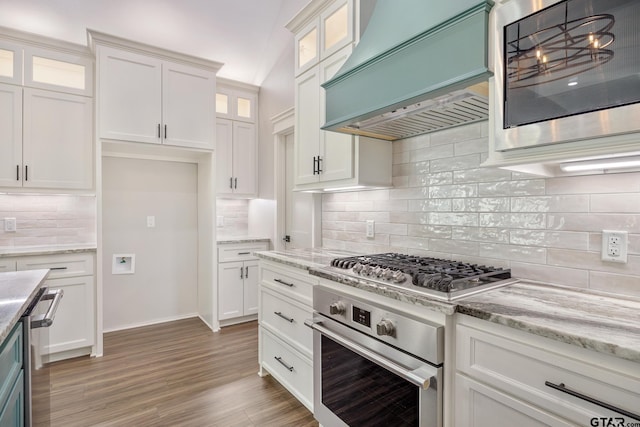 9161 Cave Branch Cv, Tyler, TX 75703 - kitchen featuring stainless steel appliances, custom exhaust hood, white cabinetry, tasteful backsplash, and light stone countertops