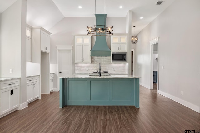 kitchen with a notable chandelier, built in microwave, hanging light fixtures, and dark wood-type flooring